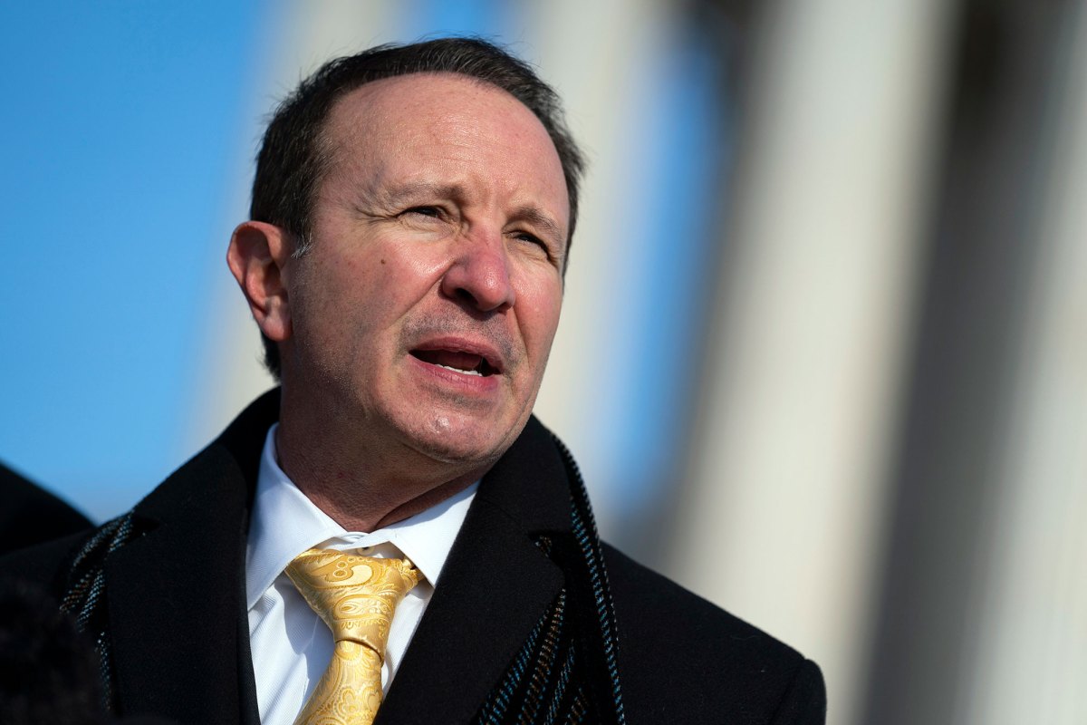 A man in a winter coat and tie stands outside