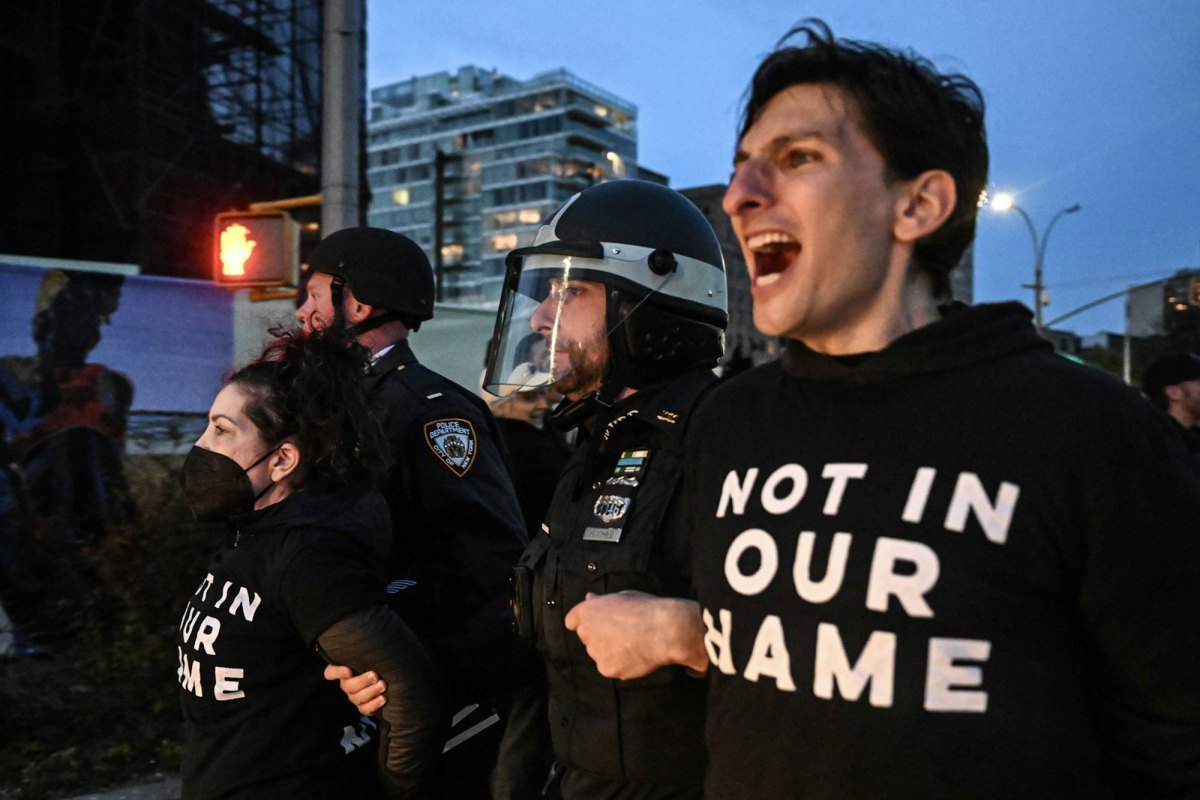 Police escort people wearing "Not in our Name" off by the arms