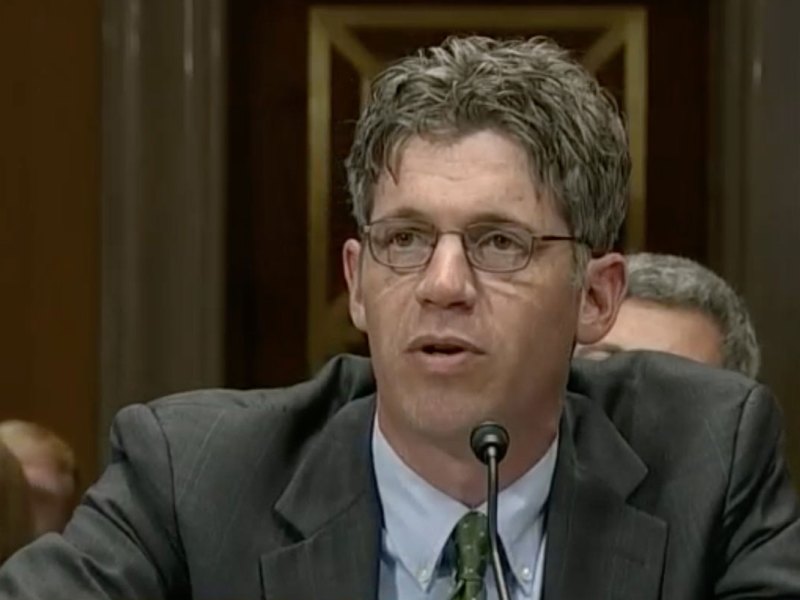 A man in a grey suit speaking at a congressional hearing