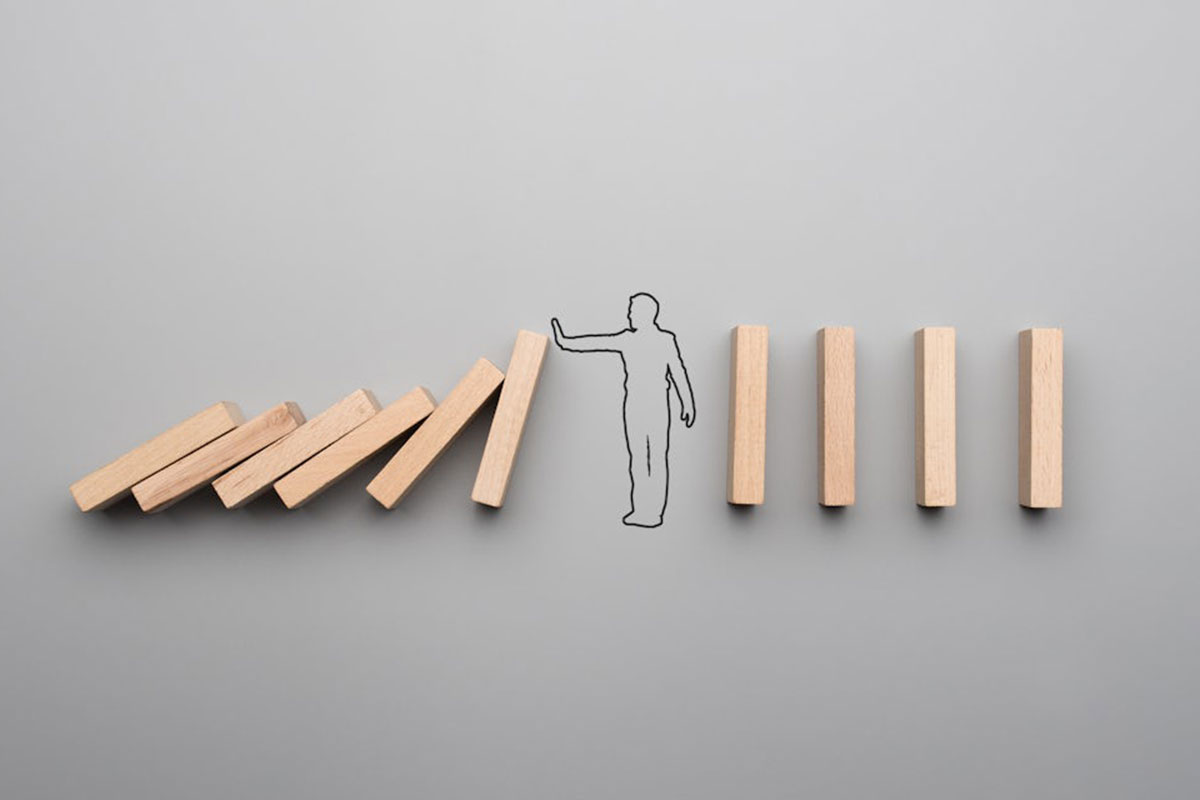 The outline of a person with hand held forward is drawn on a grey background. It's "holding" wooden blocks that are falling forward.