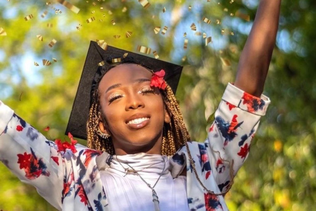 A person in a floral jacket and graduation gap throws golden confetti in the air
