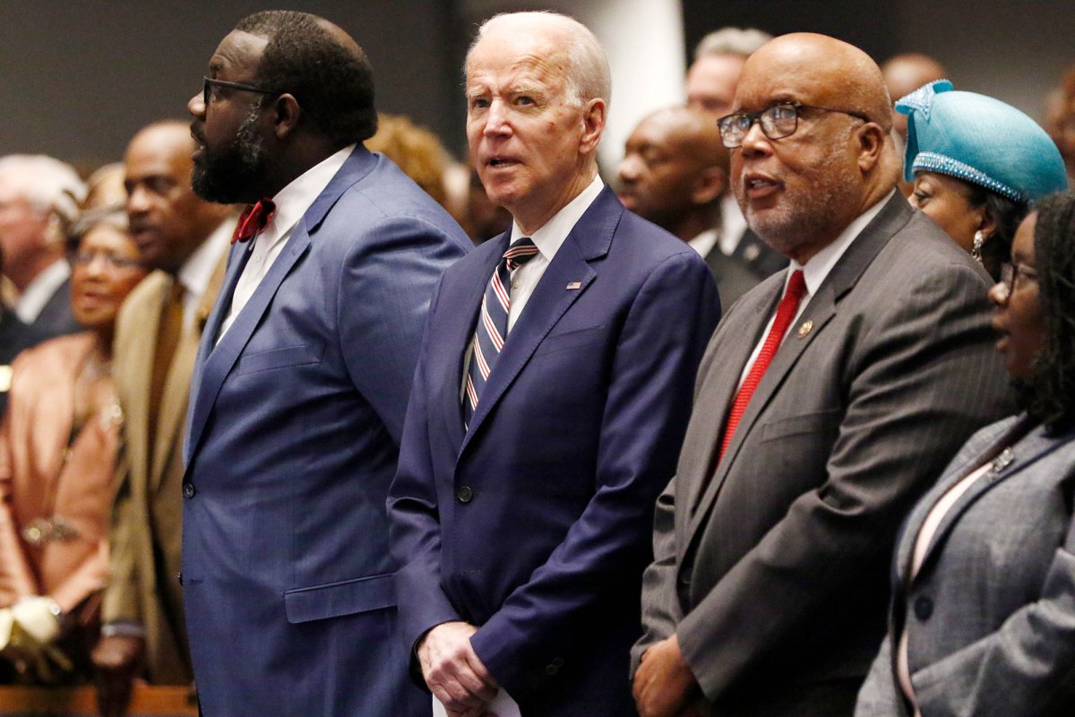 A row of men in suits including Joe Biden and Bennie Thompson stand and attend a church service