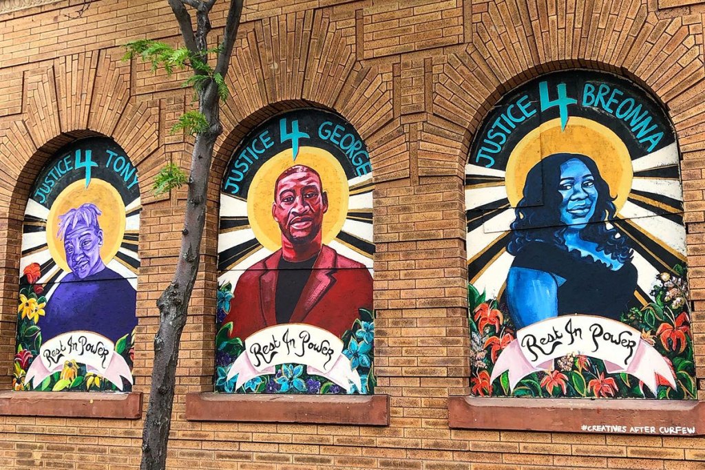 Three colorful murals painted in decorative insets in a brick wall
