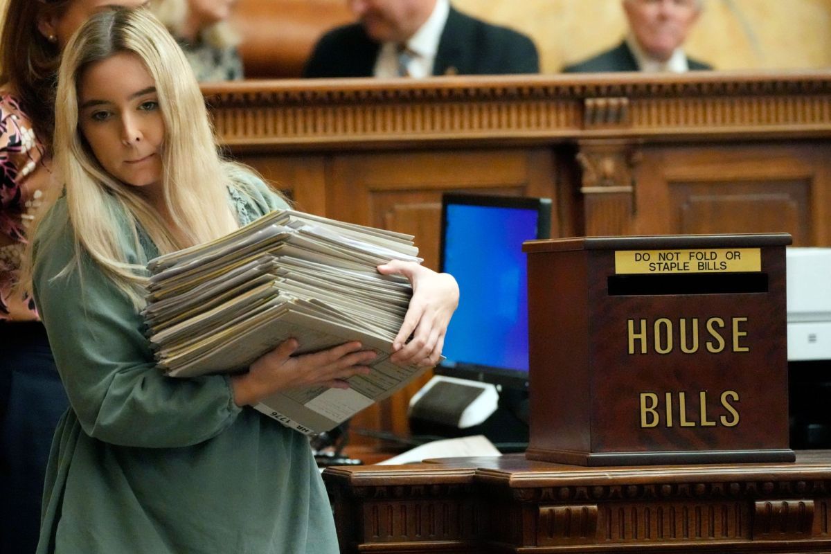 A Mississippi House clerk intern struggles to remove an armload of legislative jackets from the chamber at the state Capitol