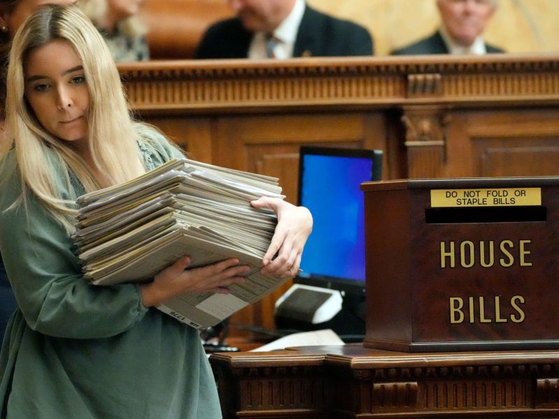 A Mississippi House clerk intern struggles to remove an armload of legislative jackets from the chamber at the state Capitol