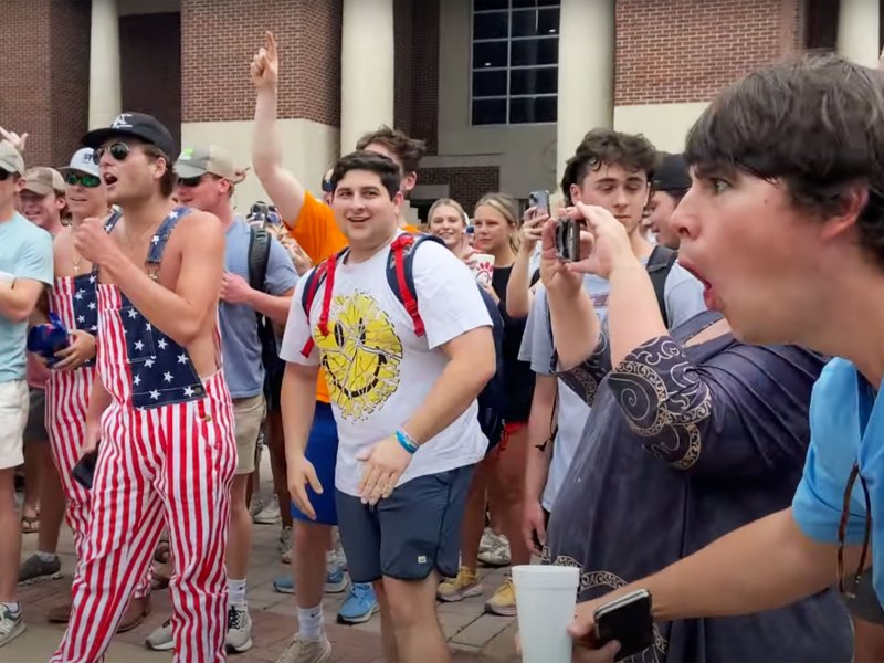 A crowd of white male ole miss students laughing and making obscene jeers