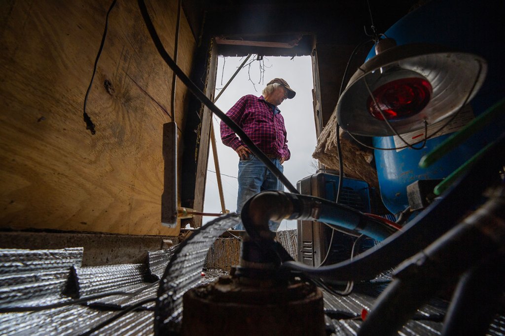 a man stands in a dilapidated wellhouse in front of equipment