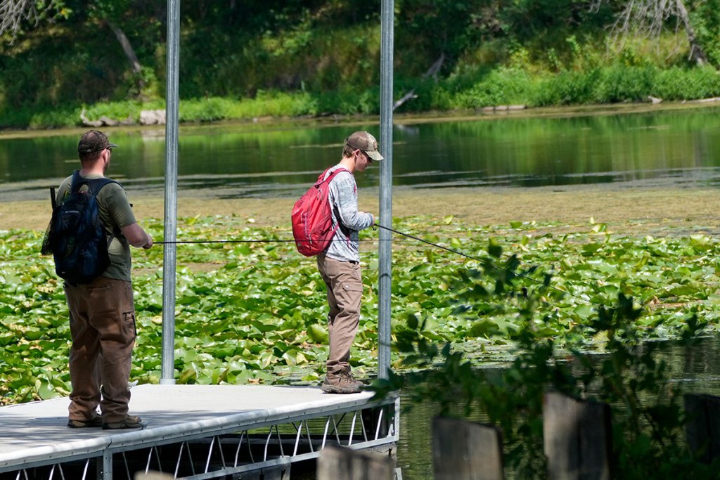 a man and his son fish off a pier in a lake