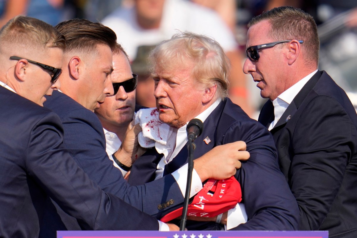 Trump, his face bloody, surrounded by secret service agents
