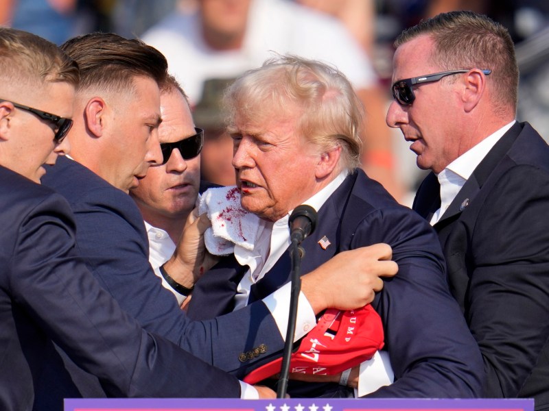 Trump, his face bloody, surrounded by secret service agents