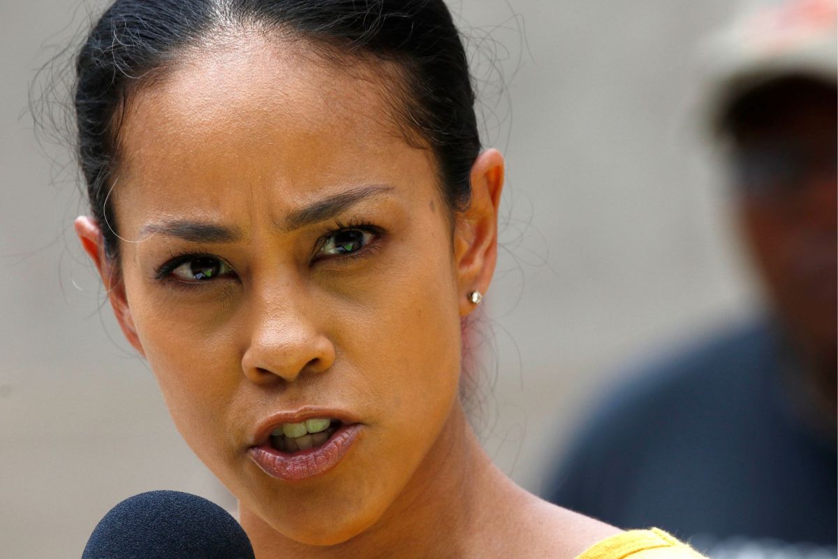 Closeup of a woman in a yellow top speaking at a mic