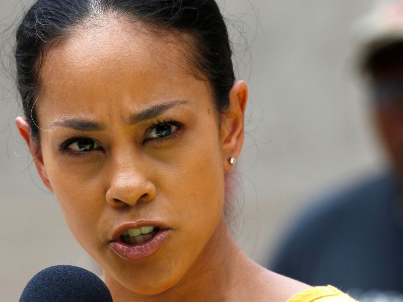 Closeup of a woman in a yellow top speaking at a mic