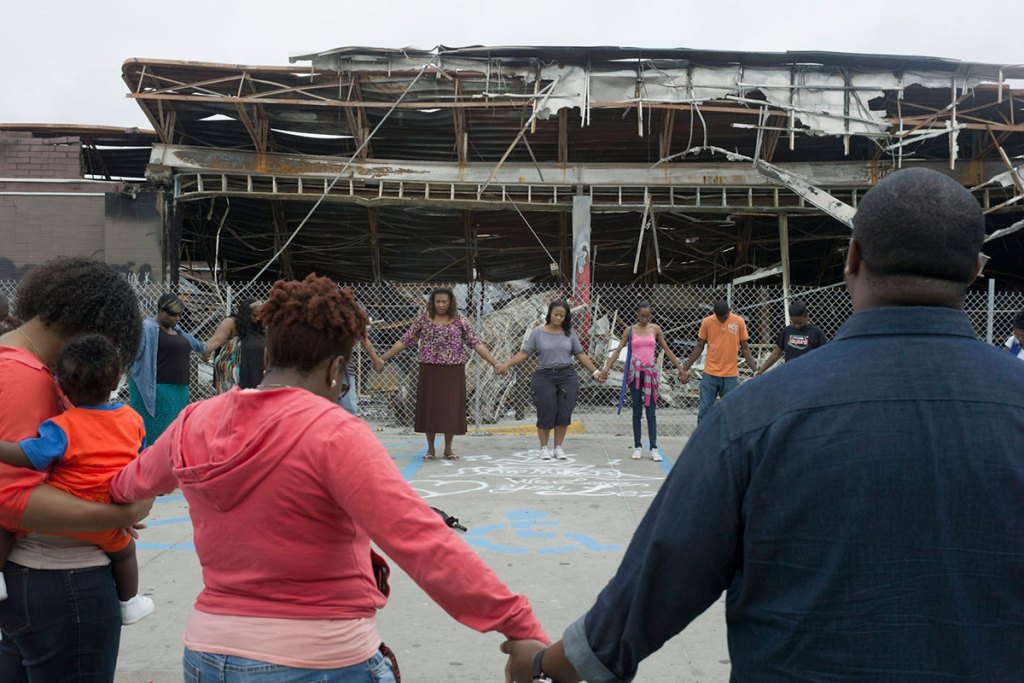 group of Black people are holding hands while standing in a circle.