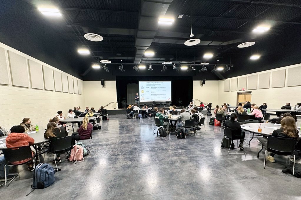 A large room filled with round tables, and teens sitting around each table