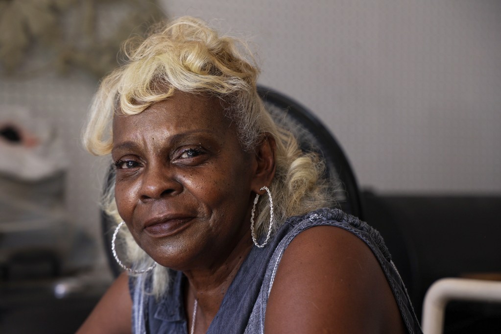 A closeup of a woman with blonde hair and large silver hoop earrings sitting inside