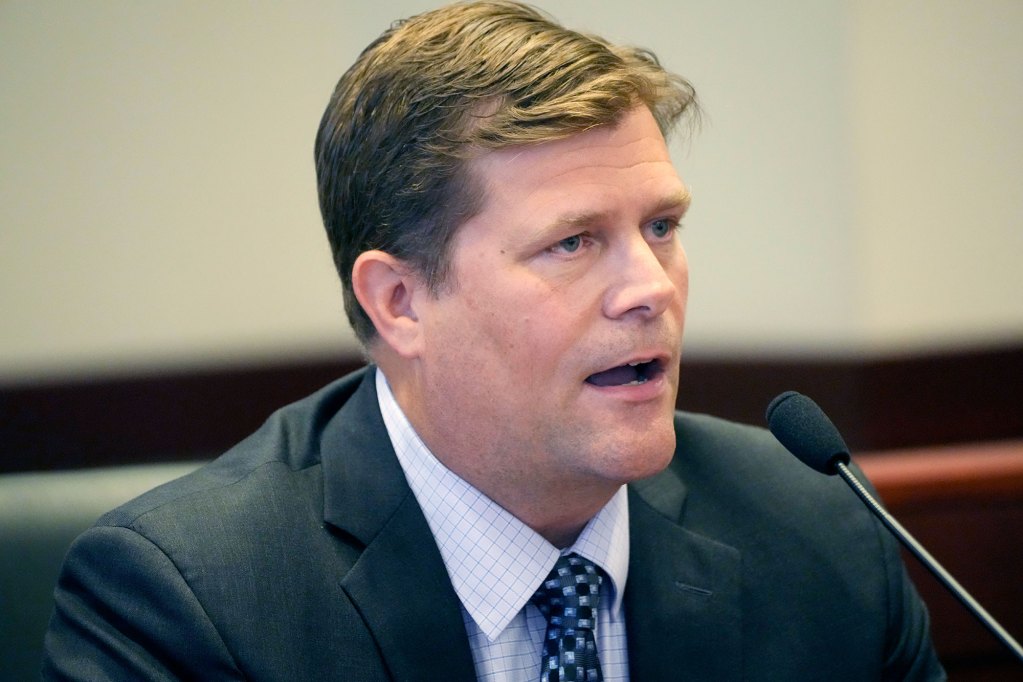 A man in a suit speaks at a mic