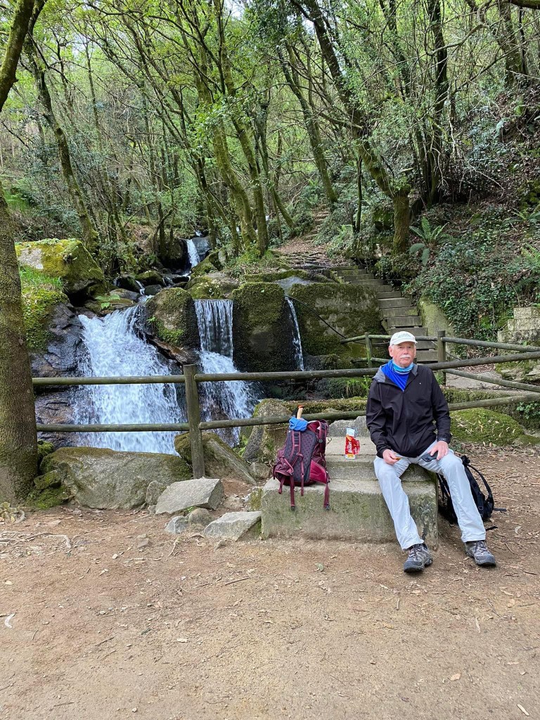 Man sitting in front of a waterfall in El Camino