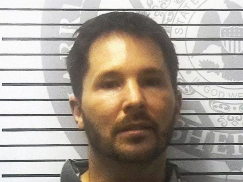 A mugshot of a man against a wal with height line marks