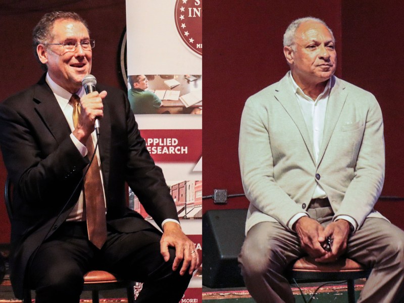 A side by side photo of two men speaking at an event inside a red room