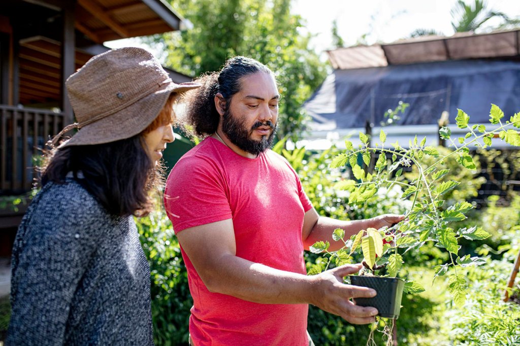 woman and man talking about a potted plant in garden