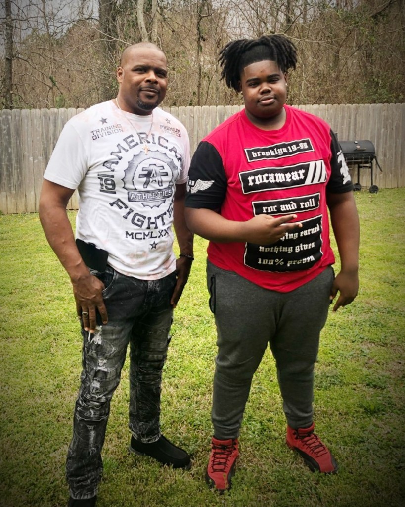 Two men stand outside in the backyard.