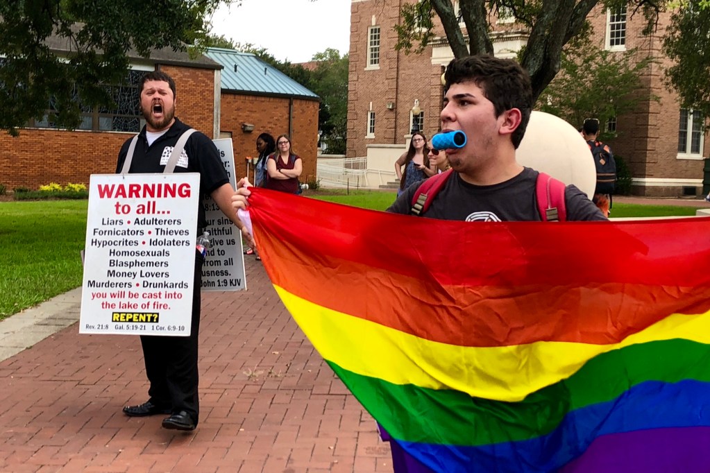 Anti LGBTQ protestors stand outside a college campus