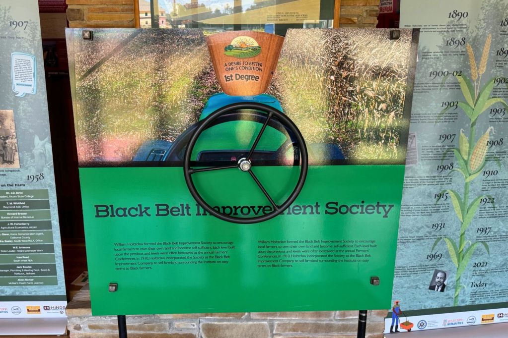 An exhibit in the Utica Institute Museum labeled Black Belt Improvement Society with a tractor wheel in the display