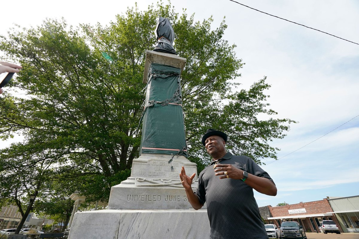 A man stands outside beside a tall confederate memorial statue