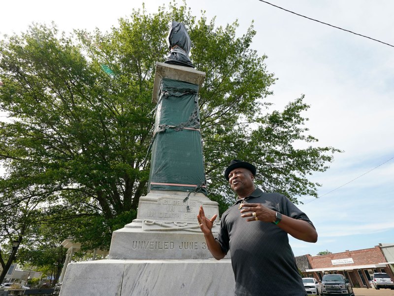 A man stands outside beside a tall confederate memorial statue