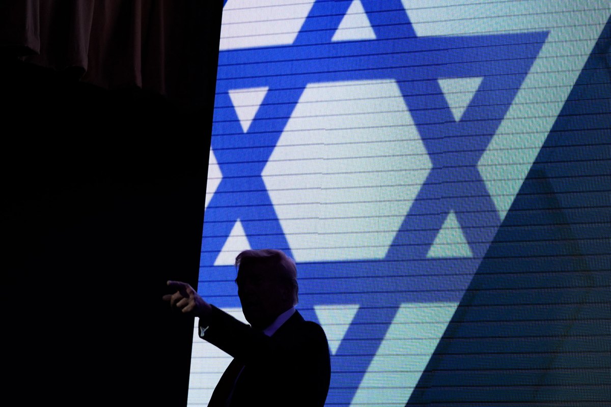A silhouette of Donald Trump is seen in front of a projection of the Star of David
