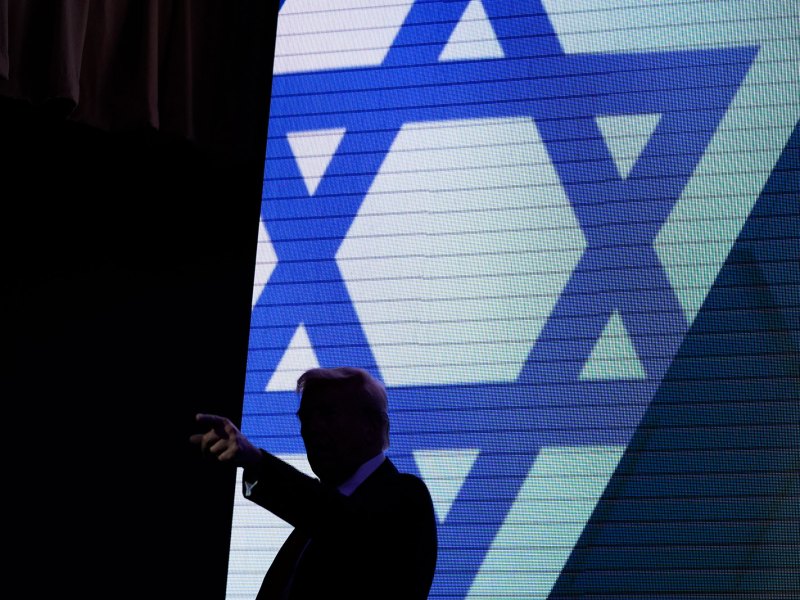A silhouette of Donald Trump is seen in front of a projection of the Star of David