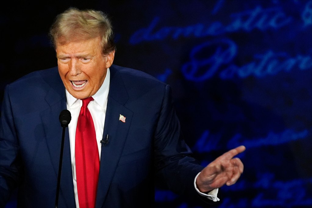 Donald Trump speaking at a mic, hand pointing off to the right