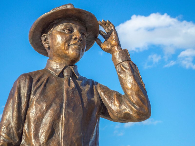 Bronze statue of Emmett Till against a blue sky