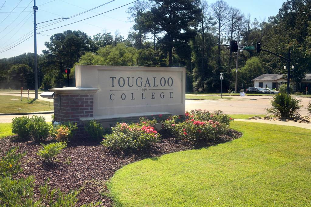 A white concrete sign that reads Tougaloo College 1869 sitting on a landscaped and floral lawn