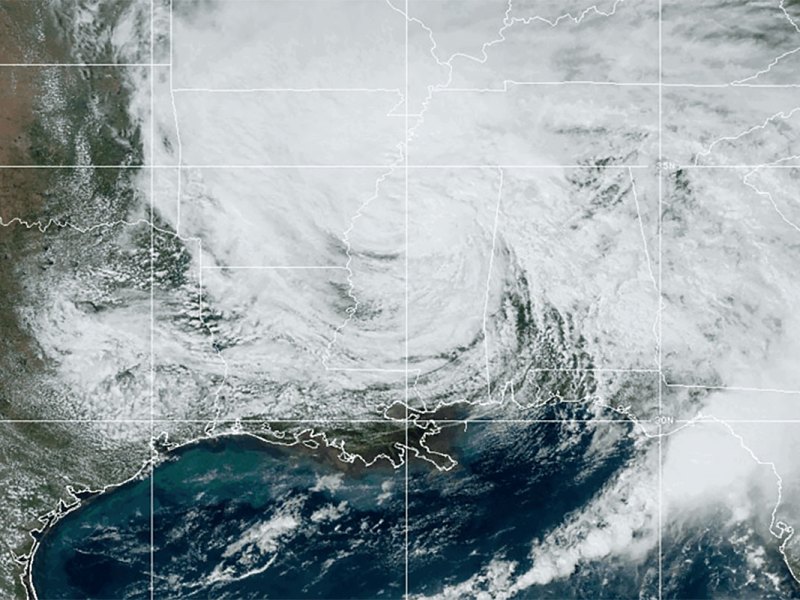 A weather map view of a large spiral of white clouds obscuring the US South