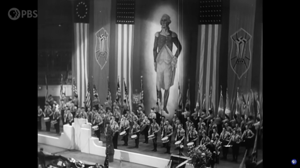 A black and white image of a Nazi rally with a large portrait of George Washington in the background