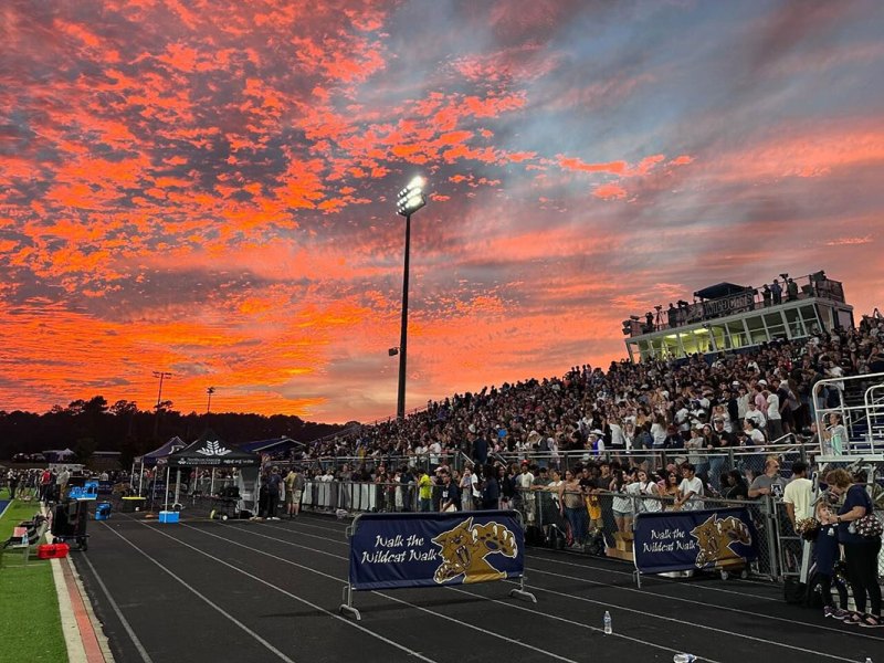 A school stadium is filled with people at sunset