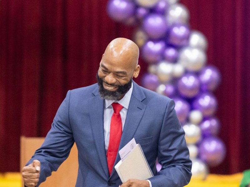 Black man smiling iniside school auditorium