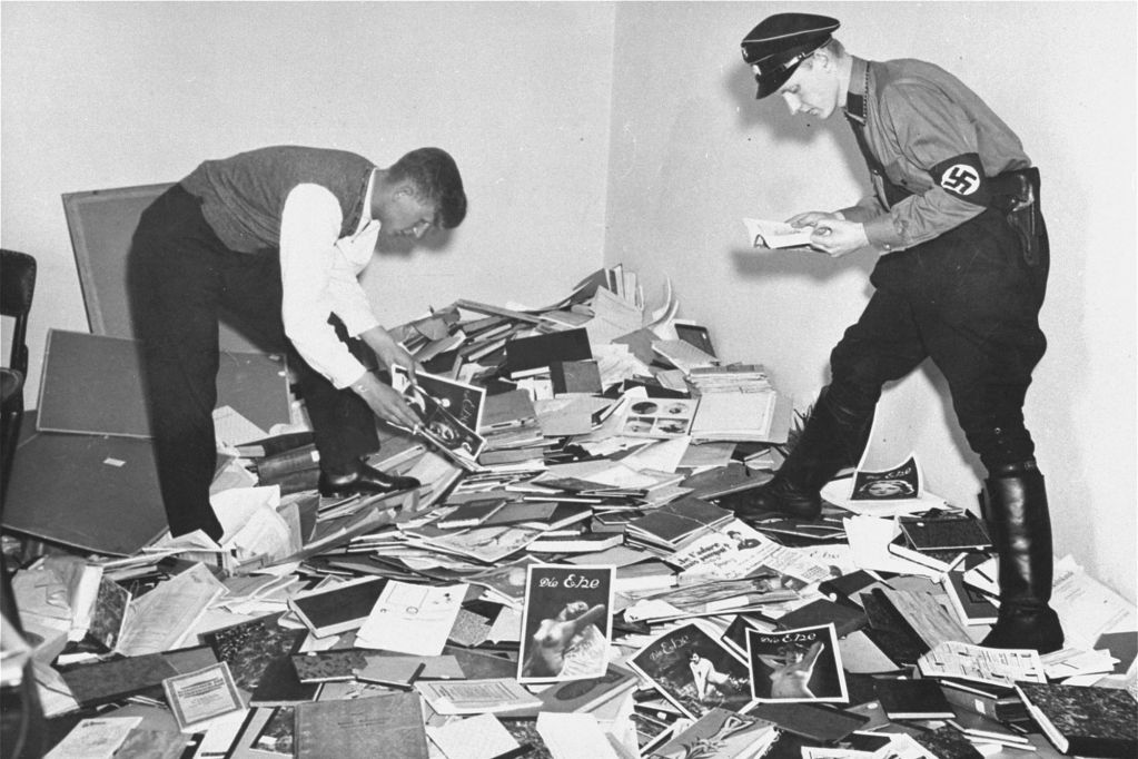 Young men, one in a SS uniform examine materials plundered from the library of Dr. Magnus Hirschfeld