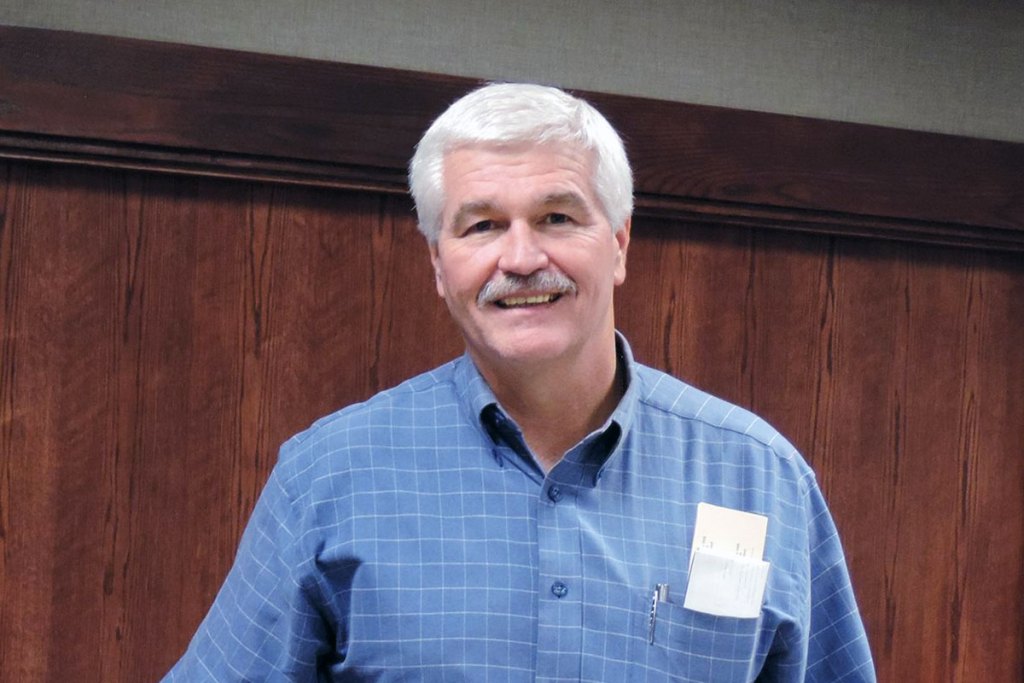 Photo of a man inside a wood paneled room
