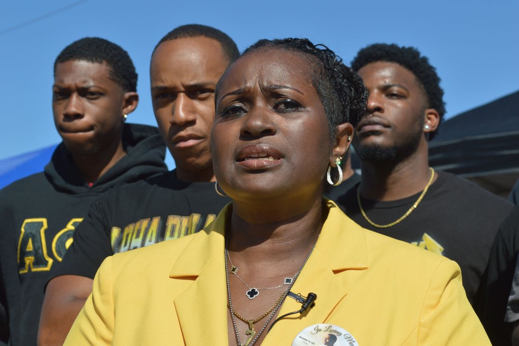 La’Trice Wright, in yellow, speaks to reporters at Stewpot