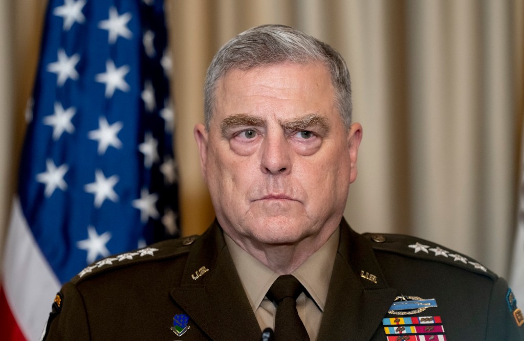 A man in a military uniform with four stars on the shoulders looks grim at a mic