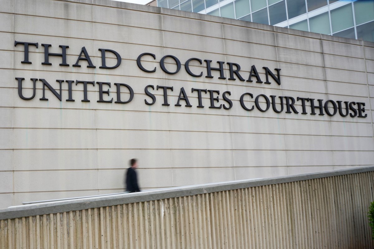 A person walks up a ramp by a wall with a sign that reads Thad Cochran United States Courthouse