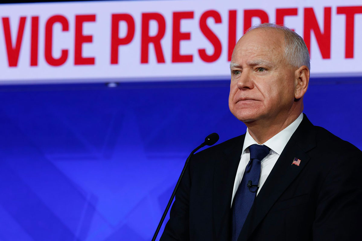 A close up of Tim Walz standing on stage before a sign that reads Vice President