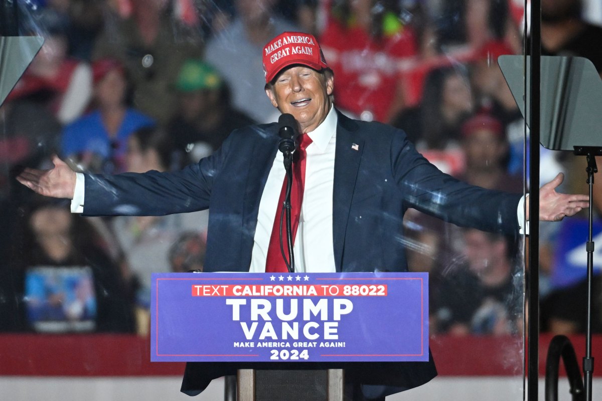 Donald Trump stands in front of a rally with arms out wide