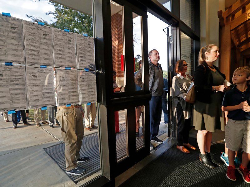 People stand in line through an open doorway to vote