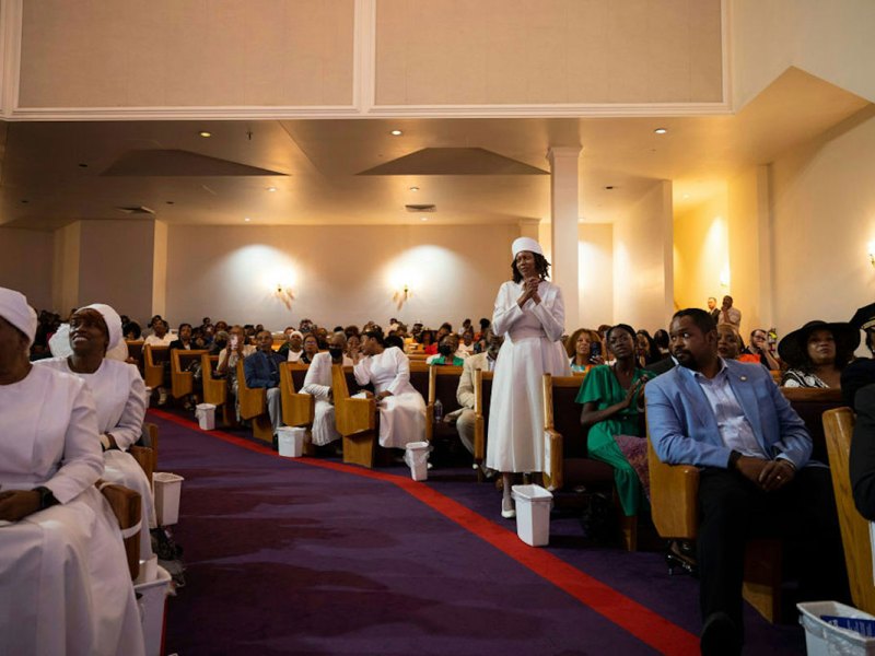 A view down the aisle of people sitting in pews, attending church