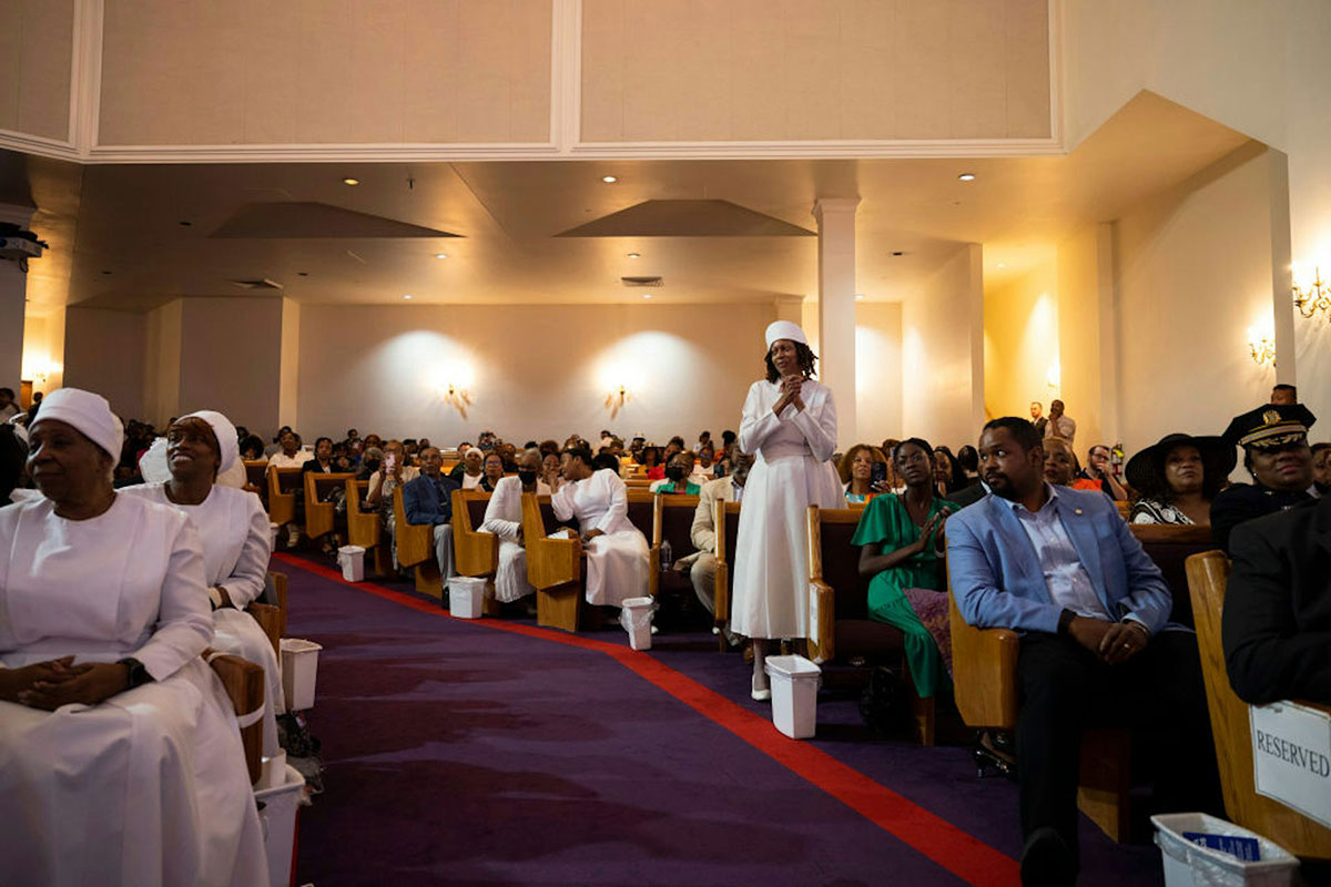 A view down the aisle of people sitting in pews, attending church