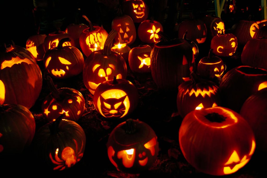 a collection of lit jack-o-lanterns lit in the dark