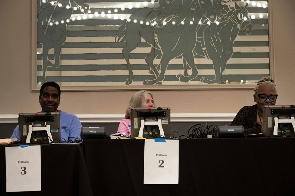 hree people sitting at computer screens at a table with a black tablecloth on it